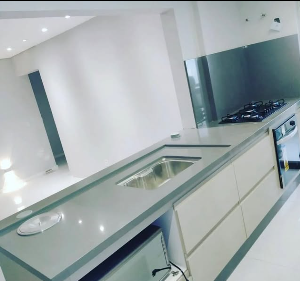 Bancada clara de cozinha com cuba de inox e cooktop